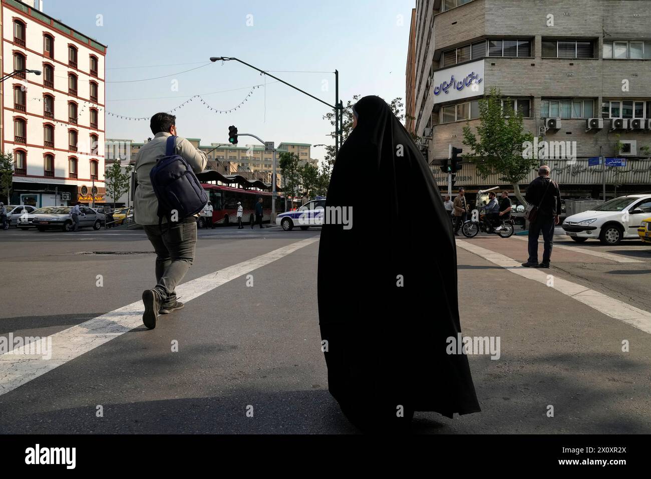 People cross an intersection in downtown Tehran, Iran, Sunday, April 14, 2024. Israel on Sunday hailed its air defenses in the face of an unprecedented attack by Iran, saying the systems thwarted 99% of the more than 300 drones and missiles launched toward its territory. (AP Photo/Vahid Salemi) Stock Photo