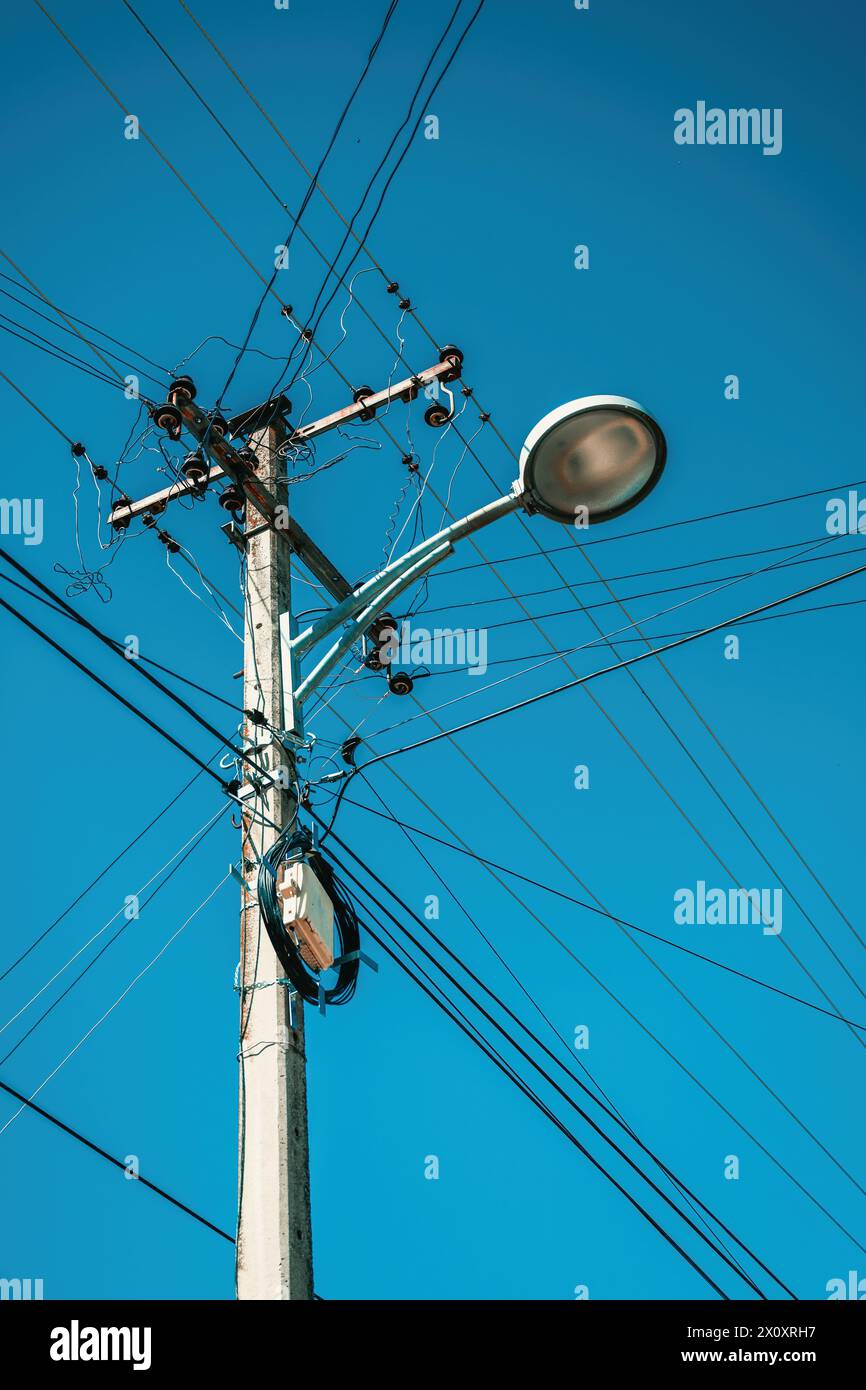 Street light with electricity utility pole and messy electrical wires, low angle view Stock Photo