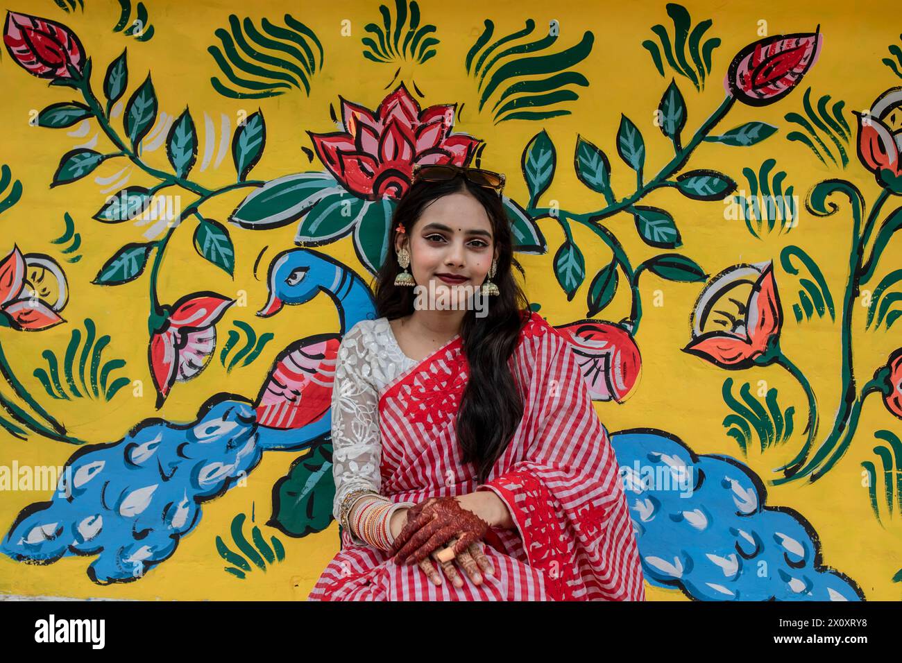 Dhaka, Bangladesh. 14th Apr, 2024. A kid poses for a photo in front of a graffiti during the celebration of the first day of the Bengali New Year, in Dhaka. Thousands of Bangladeshi people celebrate the first day of the Bengali New Year or Pohela Boishakh, with different colorful rallies, cultural programs with traditional dance and music, this Bengali year was introduced during the regime of Emperor Akbar to facilitate revenue collection in the 16th century. Credit: SOPA Images Limited/Alamy Live News Stock Photo