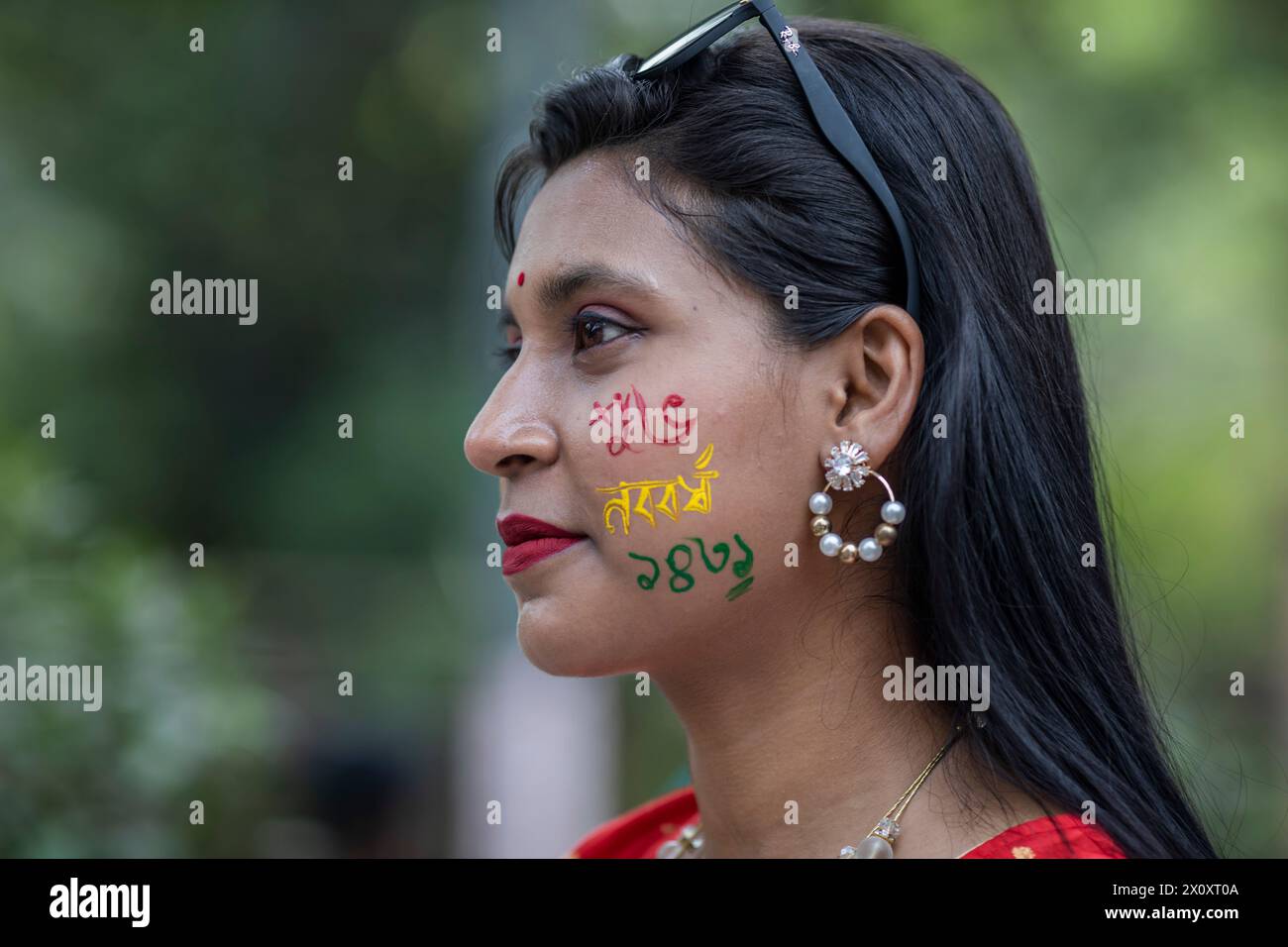 Dhaka, Bangladesh. 14th Apr, 2024. A woman seen with paintings on her cheek during the celebration of the first day of the Bengali New Year, in Dhaka. Thousands of Bangladeshi people celebrate the first day of the Bengali New Year or Pohela Boishakh, with different colorful rallies, cultural programs with traditional dance and music, this Bengali year was introduced during the regime of Emperor Akbar to facilitate revenue collection in the 16th century. Credit: SOPA Images Limited/Alamy Live News Stock Photo