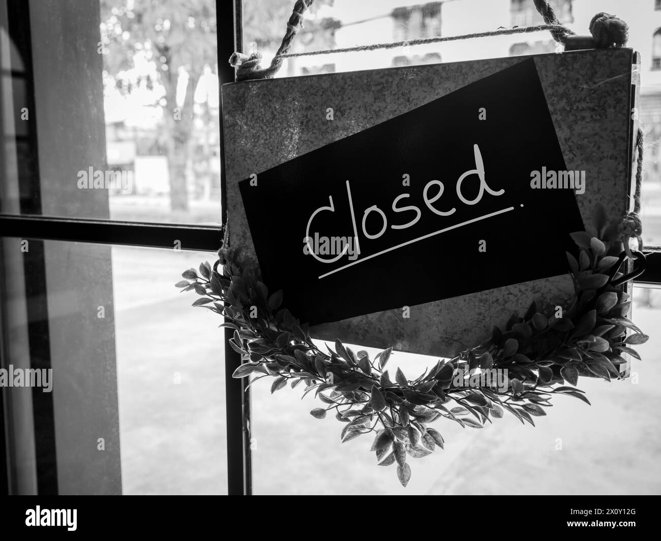 Shop closed, black notice sign with words 'CLOSED !' hanging on glass door in front of the staircase in the hotel or restaurant, black and white photo Stock Photo