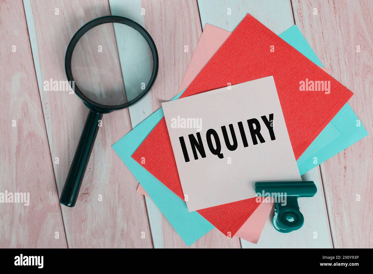 Inquiry word on colorful adhesive paper with magnifying glass. Stock Photo