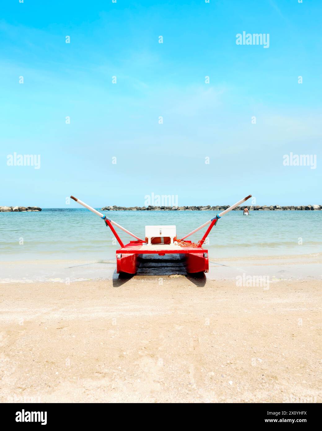 Lifeboat with lifebuoy and oars on the beach in a sunny summer day, in the background the Adriatic sea, Italy. Stock Photo