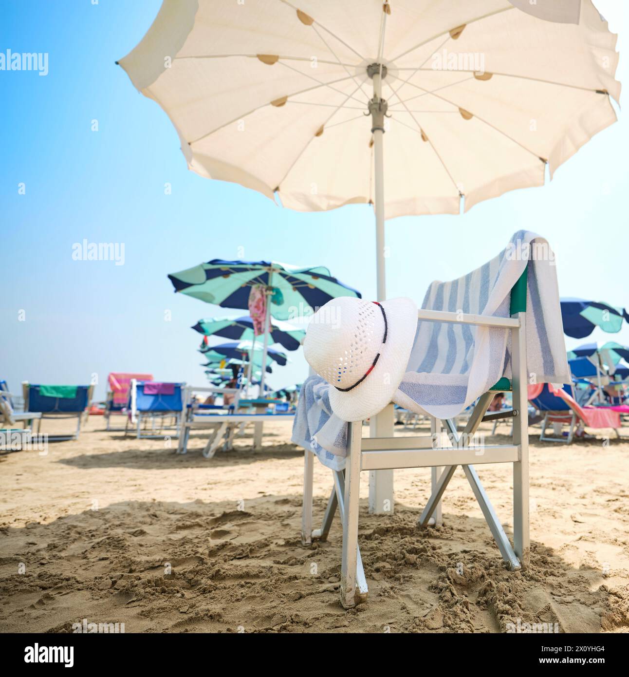 Chair with white straw hat and striped towel under a beach umbrella on ...