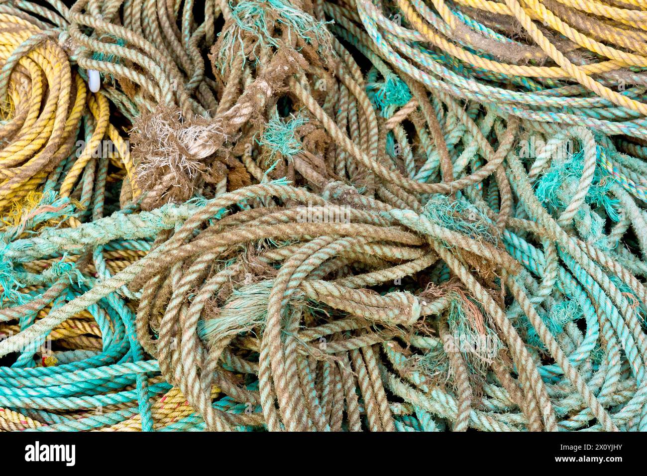 Close up abstract shot of a tangle of rope or ropes used in the fishing industry stacked loosely on the quayside of Arbroath harbour. Stock Photo