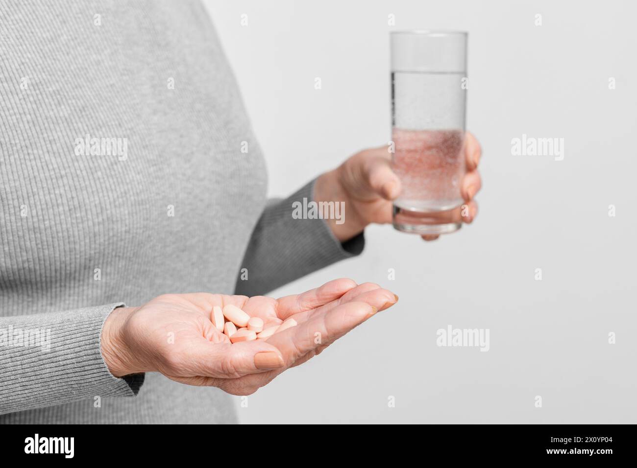 Senior holding pills and a glass of water Stock Photo
