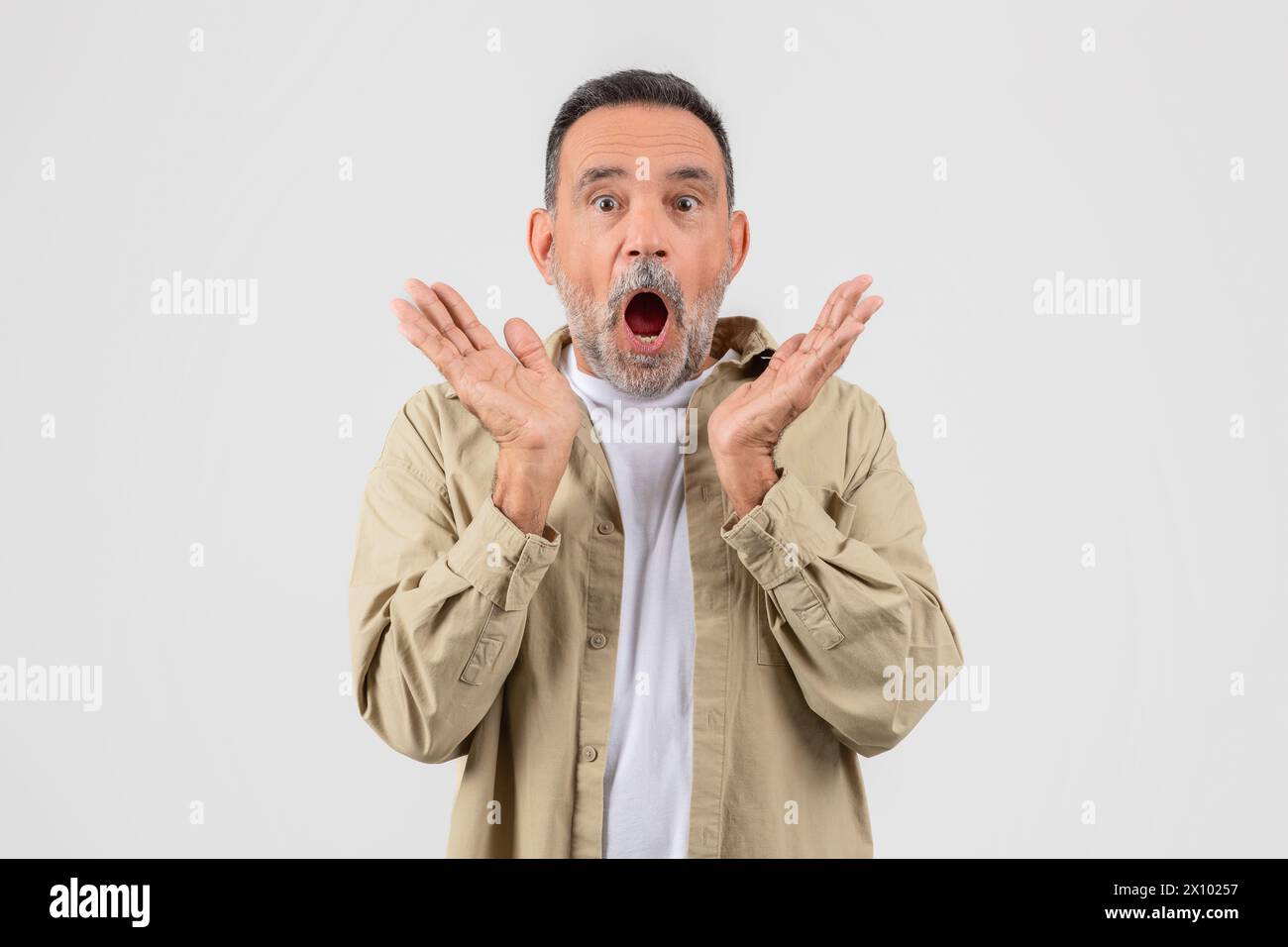 Surprised senior expressing shock with hands raised Stock Photo
