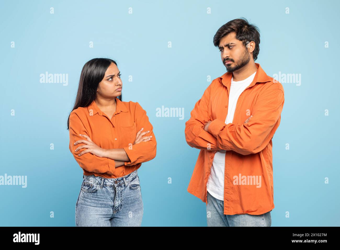 Couple in disagreement with arms crossed on blue background Stock Photo