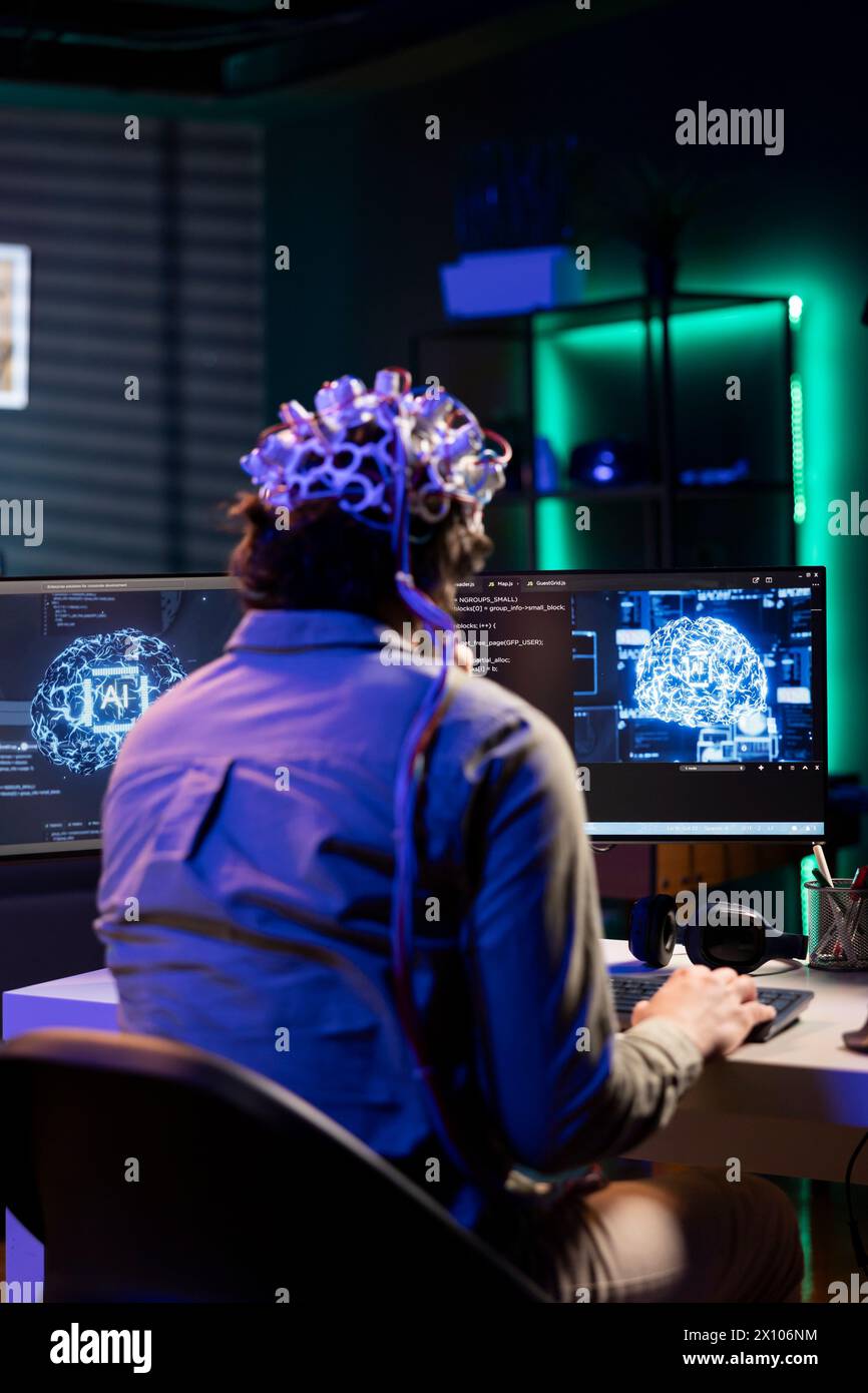 Software technician with EEG headset on programming brain transfer into computer virtual world, merging with artificial intelligence. IT expert using neuroscience to gain digital soul Stock Photo