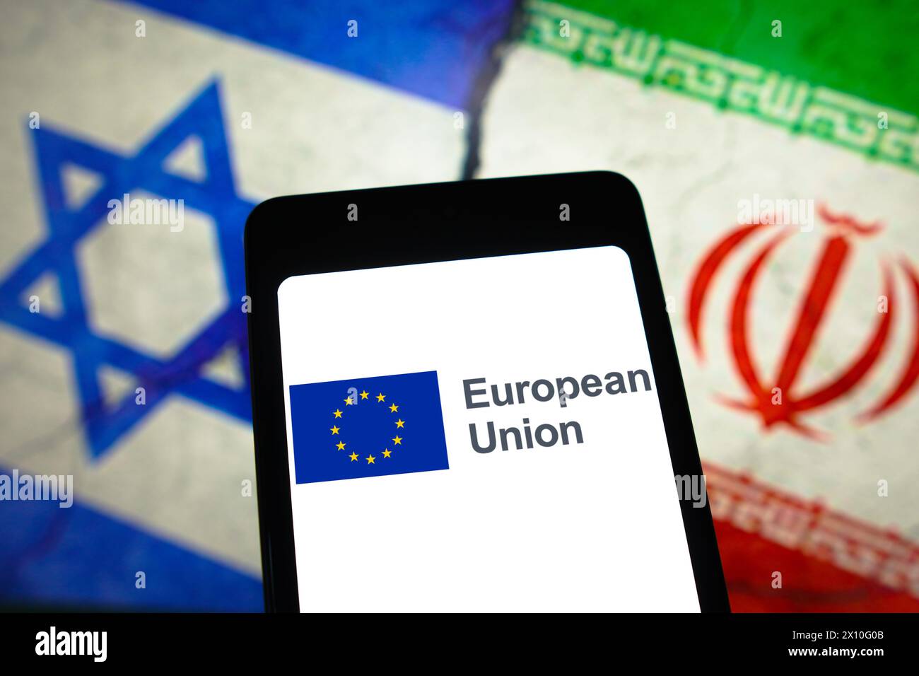 In this photo illustration, the European Union (EU) logo is displayed on a smartphone screen and flags of Israel and Iran in the background. Stock Photo
