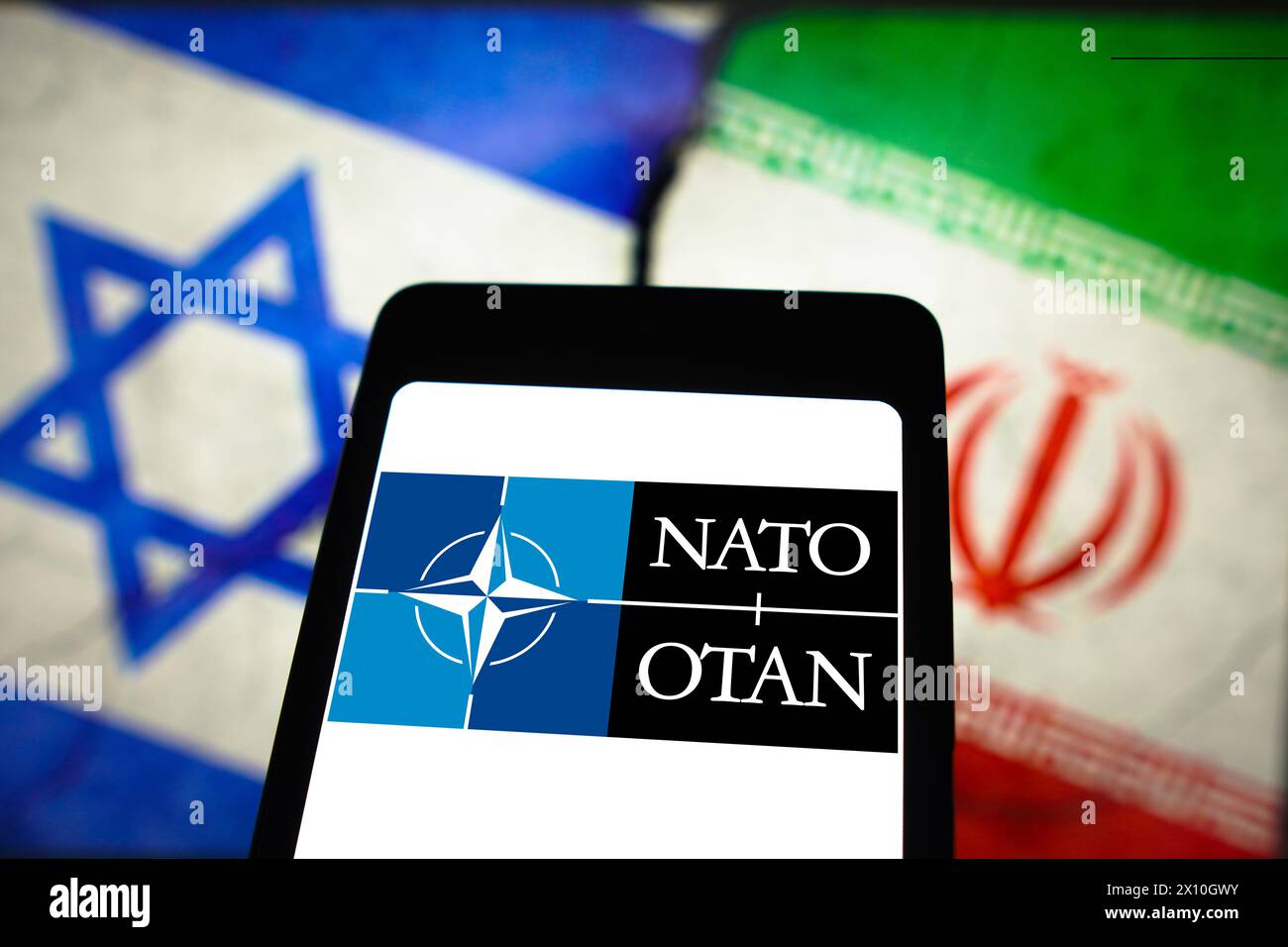 Brazil. 14th Apr, 2024. In this photo illustration, the North Atlantic Treaty Organization (NATO) logo is displayed on a smartphone screen and flags of Israel and Iran in the background. (Credit Image: © Rafael Henrique/SOPA Images via ZUMA Press Wire) EDITORIAL USAGE ONLY! Not for Commercial USAGE! Stock Photo