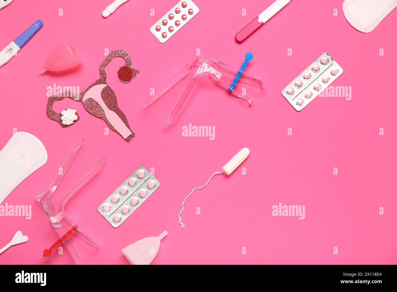 Paper uterus with pills, gynecological speculums and menstrual cups on pink background Stock Photo