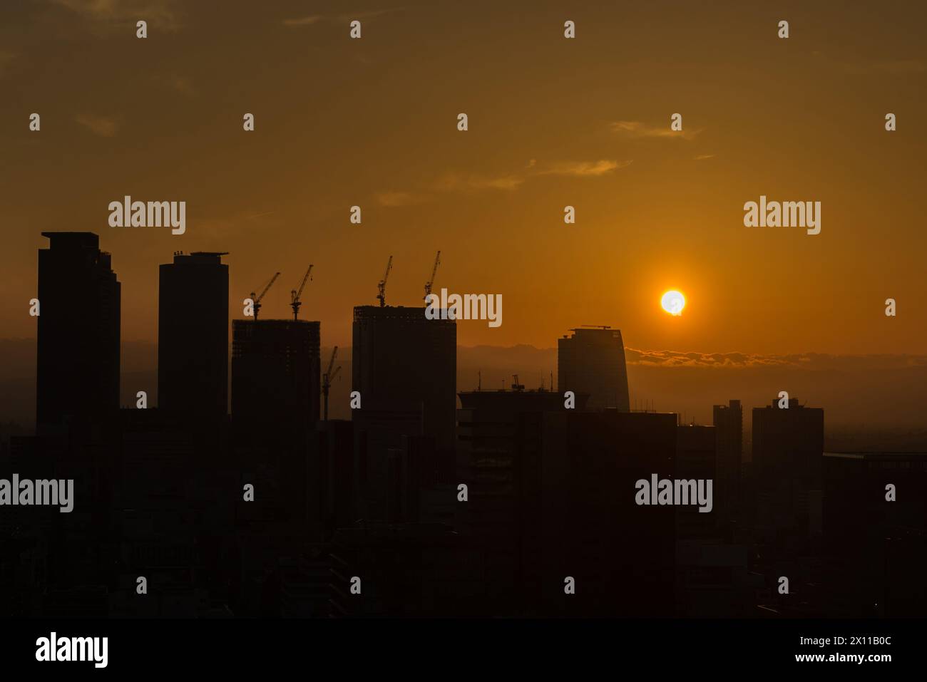 The sun is setting over a city skyline, casting a warm glow over the ...