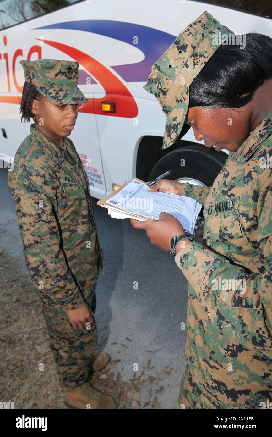 Cpl. Marie Hendrix, an administrative clerk with the 22nd Marine Expeditionary Unit Command Element, checks Lance Cpl. Denise Marcelin's name off a manifest as she boards a bus that will take her to the port at Morehead City, N.C. where she will board the USS Bataan, Jan. 15, 2010. The 22nd MEU will deploy to Haiti aboard the Bataan and USS Carter Hall and Fort McHenry to provide sea based humanitarian aid and disaster relief to the Haitian people after an earthquake ravaged the country, Jan. 12. Stock Photo