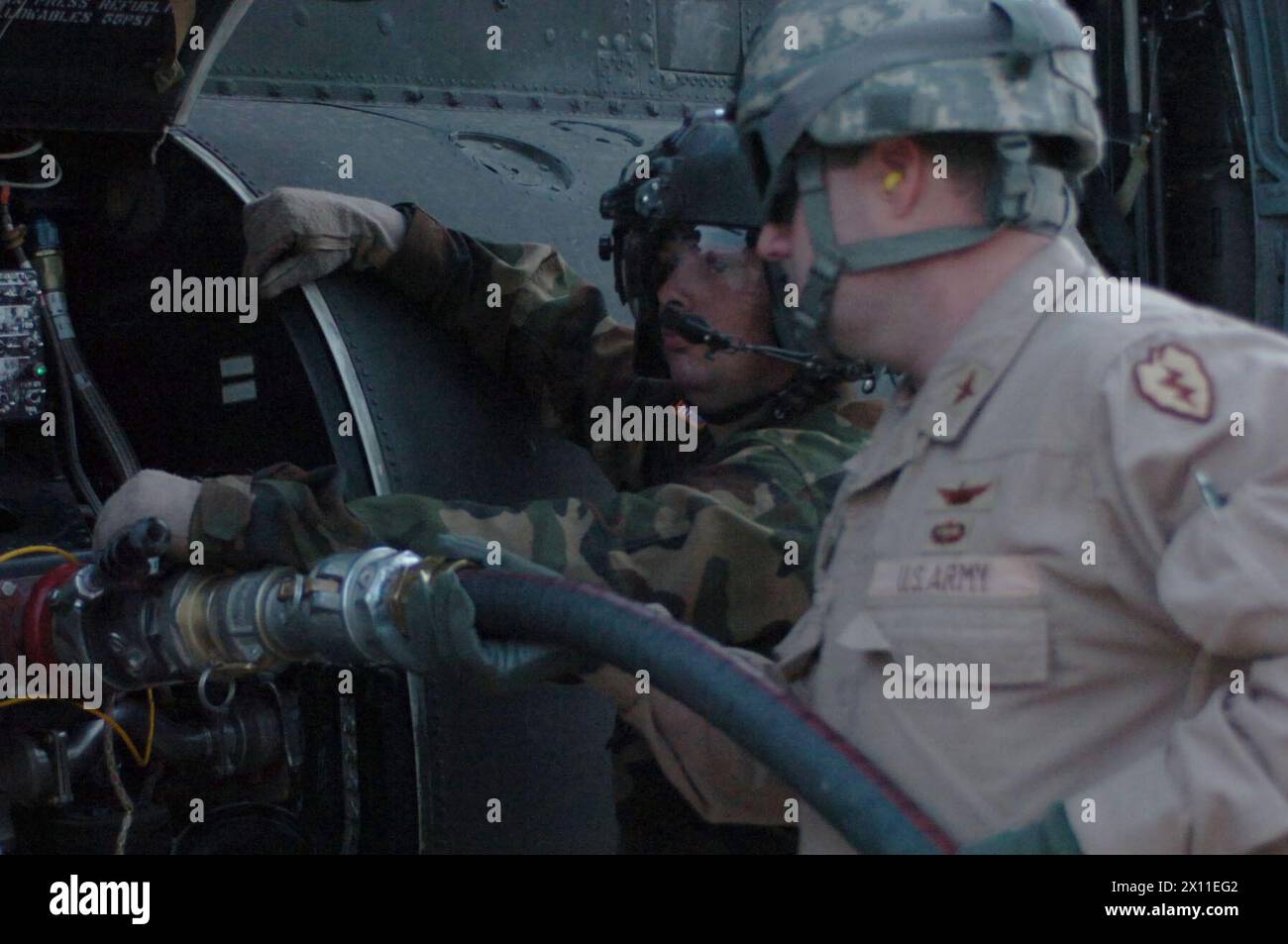 Original Caption: Lt. Col. Michael Fleetwood, commander, Echo Company, 3rd Battalion 25th Combat Aviation Brigade and Pfc. Nathan Allcock, crew chief, 3-25, pumps the one millionth gallon of fuel into a CH-47, at Contingency Operating Base Speicher ca. July 03, 2004 Stock Photo