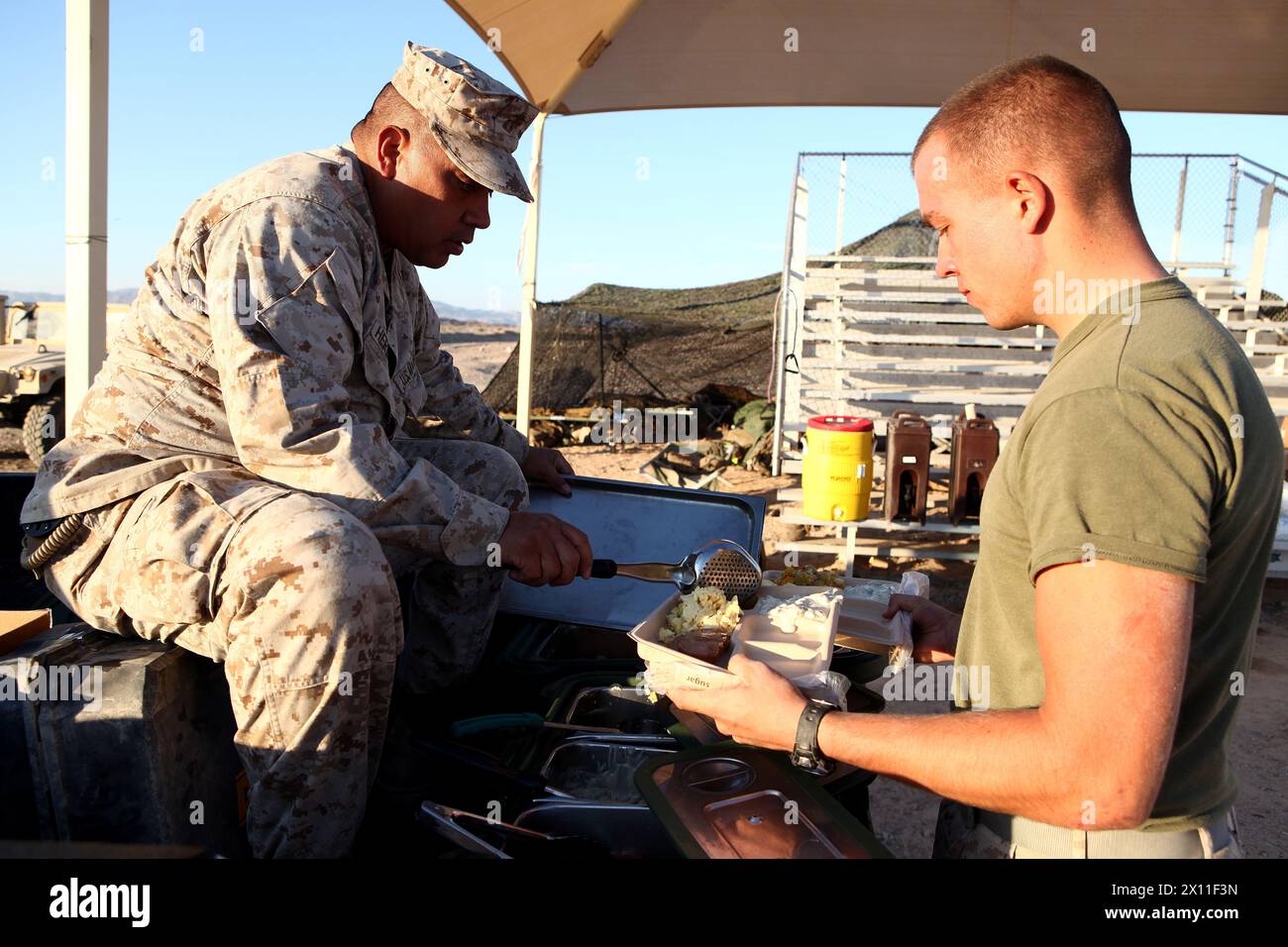 Master Gunnery Sgt. Socorro Hernandez with Combat Logistics Regiment 2, 2nd Marine Logistics Group, brings hot chow to his Marines in the field during Enhanced Mojave Viper (EMV), on Marine Corps Air Ground Combat Center Twentynine Palms, CA, Sept. 20, 2012. The Marines participate in EMV in order to build unit cohesion and  tactical proficiency in preparation for deployment in support of Operation Enduring Freedom MAGTF. Stock Photo