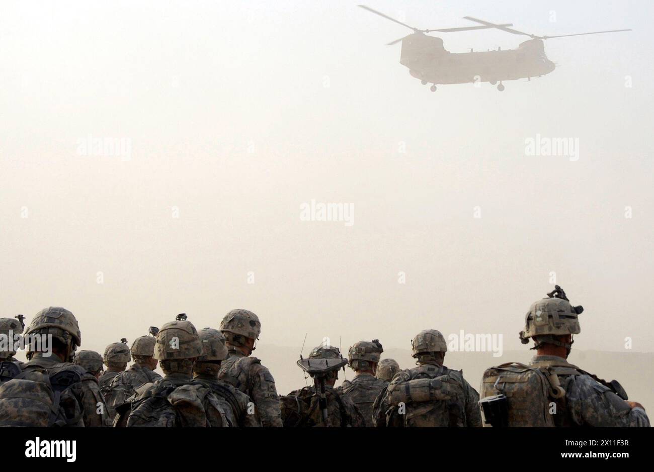 Paratroopers from the 1st Platoon, Company C, 1st Battalion, 501st Infantry Regiment, 4th Brigade Combat Team, 25th Infantry Division, watch as a CH-47 Chinook helicopter begins its decent during a dust storm at Forward Operating Base Kushamond, Afghanistan, in preparation for an air-assault mission ca. September 07, 2004 (metadata lists year as 2009) Stock Photo