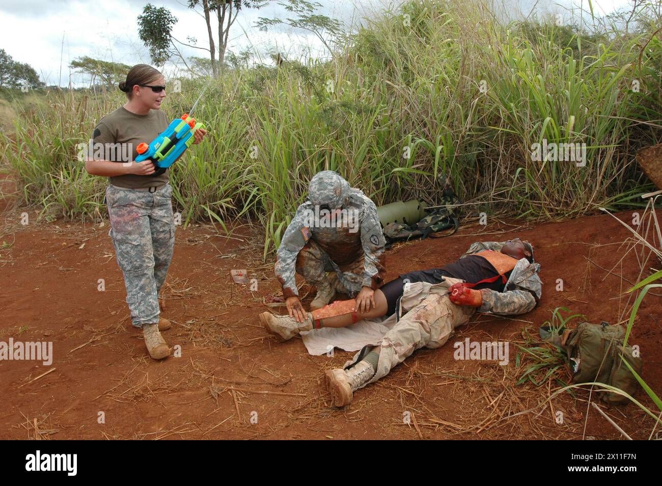 As students provide medical care to injured patients during the Combat Lifesaver Course, Spc. Jessica King, combat medic with Headquarters and Headquarters Company, 3rd Battalion 25th Aviation Regiment, 25th Combat Aviation Brigade squirts water simulating rain drops. The class allowed students to practice realistic training in battlefield situations ca. August 03, 2004 Stock Photo