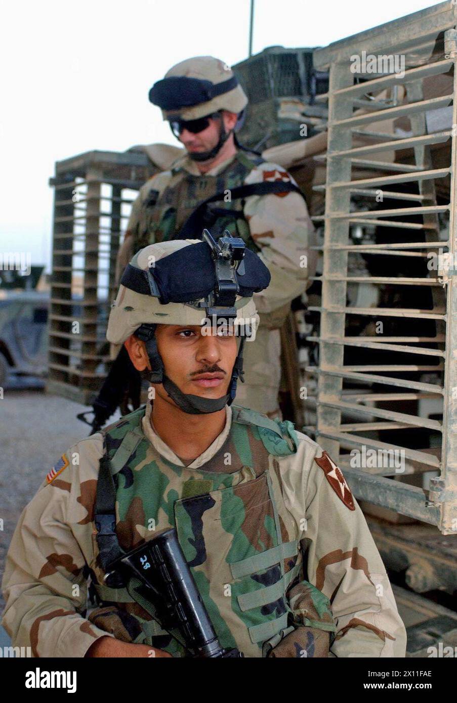 Pfc. Husam Razaq Almusowi (front) and Capt. Matthew Lillibridge exit a Stryker vehicle after returning from a mission where Almusowi translated Lillibridge's conversation to Iraqi Civil Defense Corps soldiers. Almusowi and Lillibridge are Soldiers with the 5th Battalion, 20th Infantry Regiment, 3rd Brigade, 2nd Infantry Division (Stryker Brigade Combat Team) ca. May 29, 2004 Stock Photo