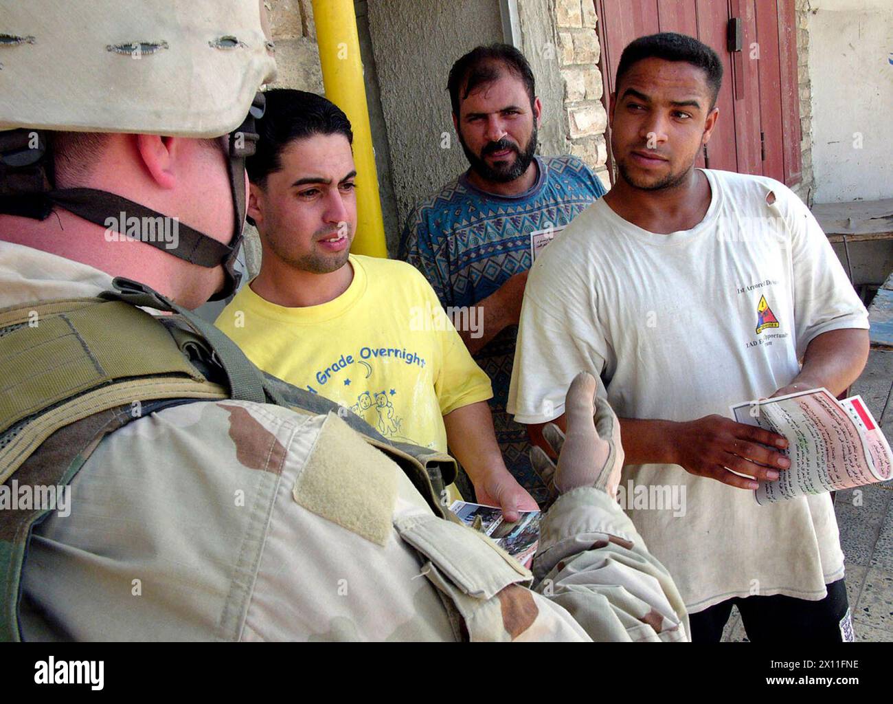 Residents of the Al Furat muhalla in the Al Rashid District of Baghdad listen to Sgt. Brian Hayes, a psychological operations specialist with the 345th PSYOP Company, talk about new and current projects by the 1st Cavalry Division during a patrol-and-greet July 30, 2024. Stock Photo