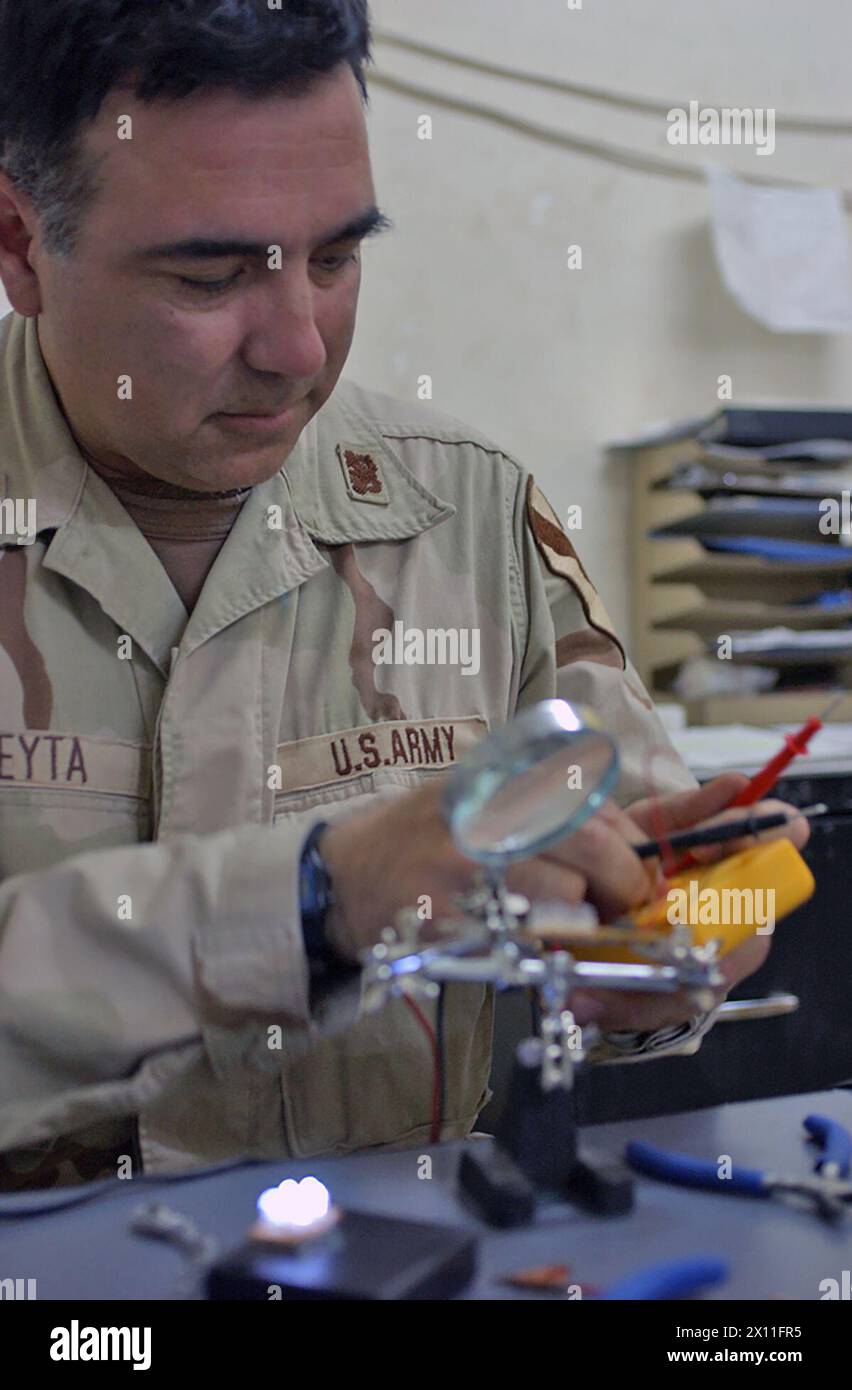 Chief Warrant Officer 2, Karl Abeyta, 4th Brigade Combat Team, 1st Cavalry Division, works on his light emitting diode (LED) prototypes.  Abeyta decided to find a new source of light to keep up with his reading habit. 'I was going through four batteries every two nights just to keep up with my reading.  I was on a constant search for batteries.'  ca. July 26, 2004 Stock Photo