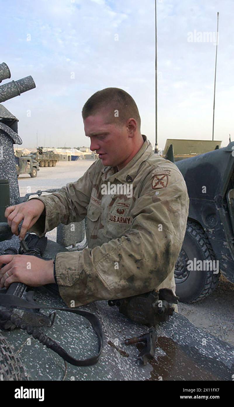Staff Sgt. James Mastrodomenico, a section sergeant with the 4th Battalion, 31st Infantry Regiment, 10th Mountain Division, conducts weapons maintenance during a stop at Combat Support Center Scania in Iraq July 18, 2004. Stock Photo