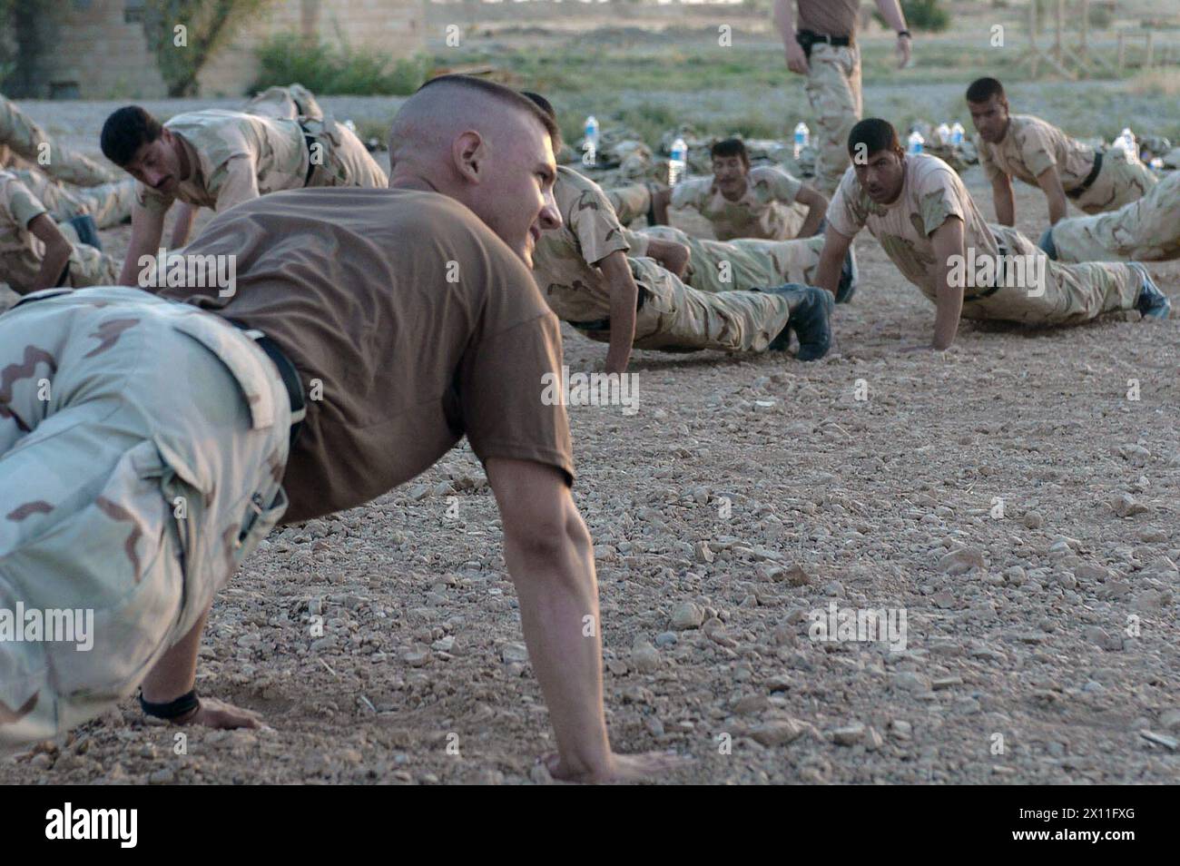 Sgt. Jaron Eckhart from Company C, 52nd Infantry Regiment, 3rd Brigade, 2nd Infantry Division (Stryker Brigade Combat Team) leads a platoon of Iraqi National Guard soldiers in physical training ca. July 14, 2004 Stock Photo