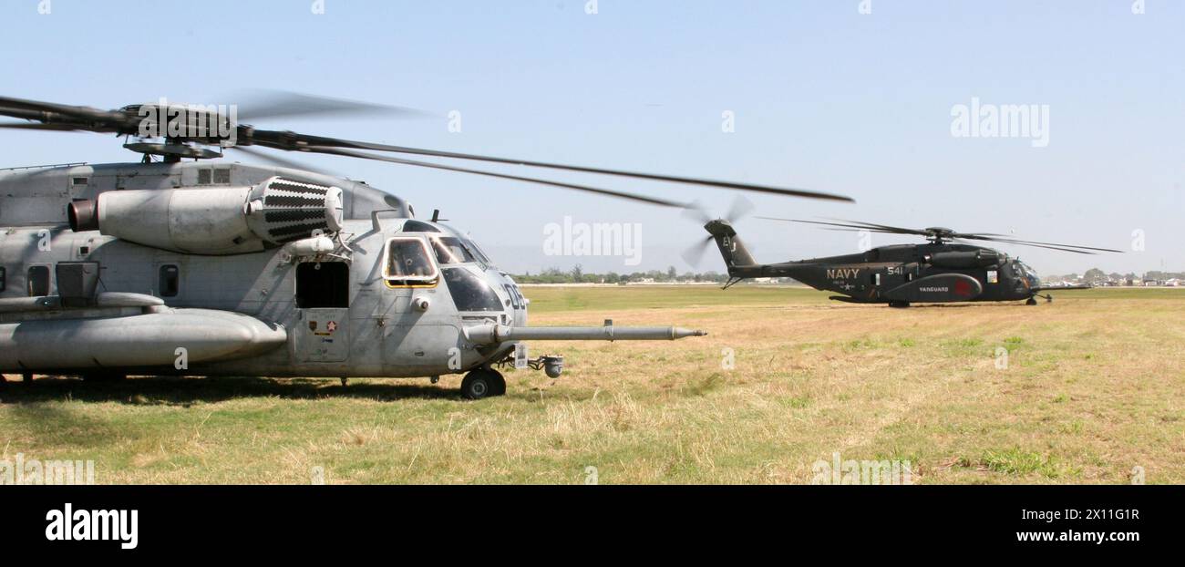 A Marine CH-53E Super Stallion helicopter from Marine Heavy Helicopter Squadron 461 (Reinforced) (left) and a Navy MH-53E Sea Dragon from Navy Helicopter Counter-Measures Squadron 14 (right) stand-by to unload their cargo at the Toussaint Louverture International Airport in Port-au-Prince, Haiti, Jan. 22, 2010. Stock Photo