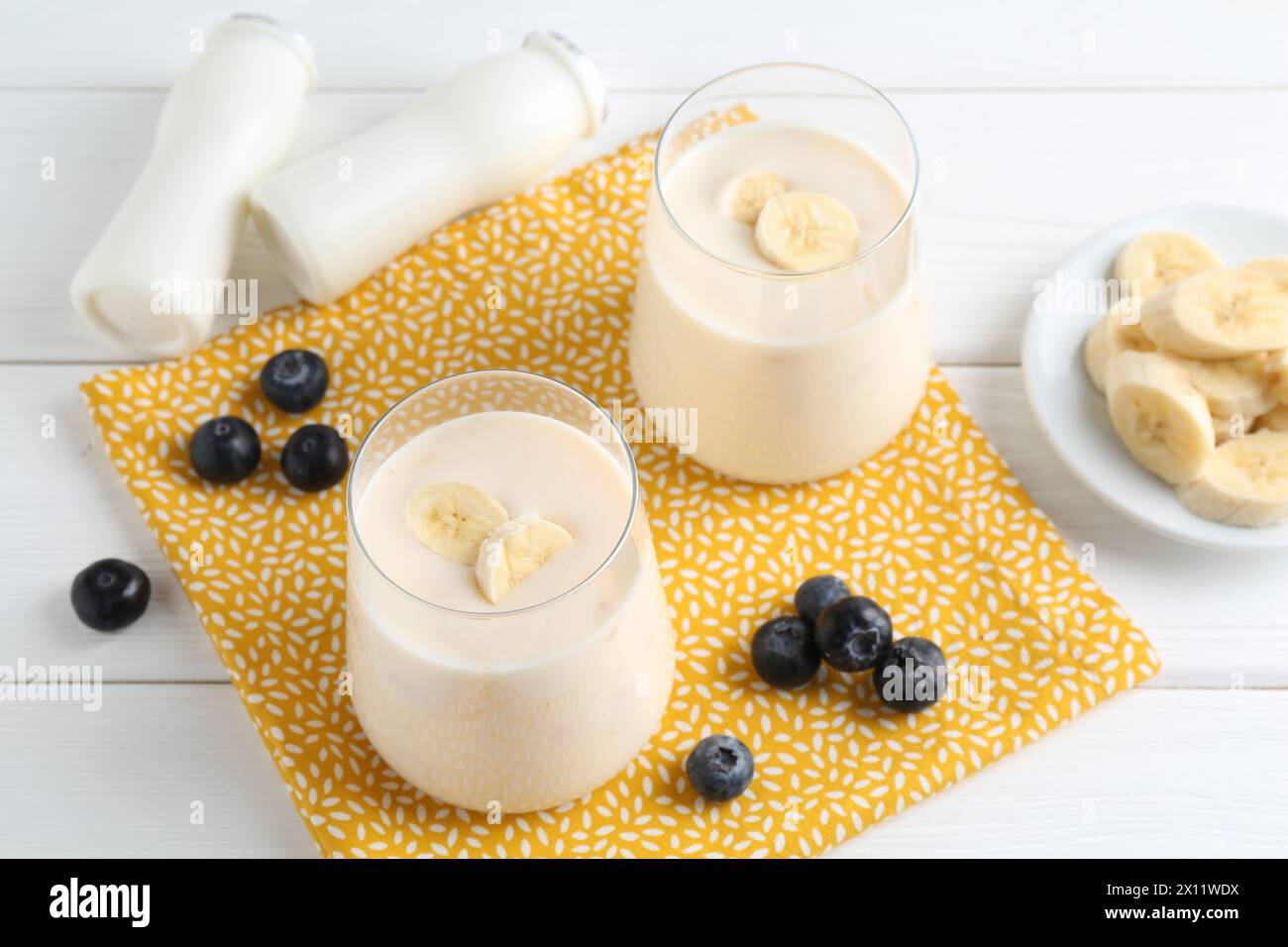 Tasty yogurt, banana and blueberries on white wooden table Stock Photo