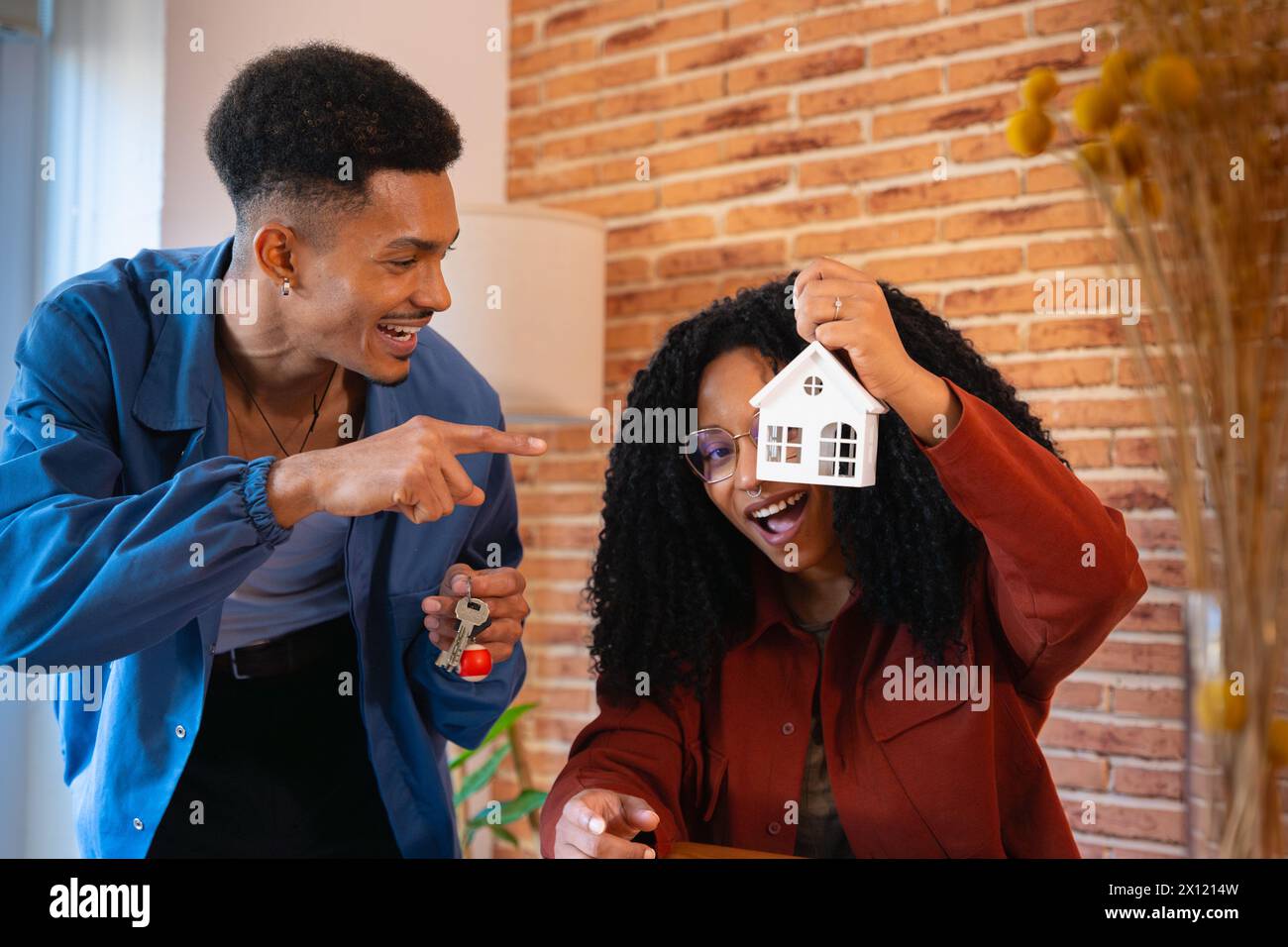 Happy multiracial couple showing a mini wooden house and a key with a ...