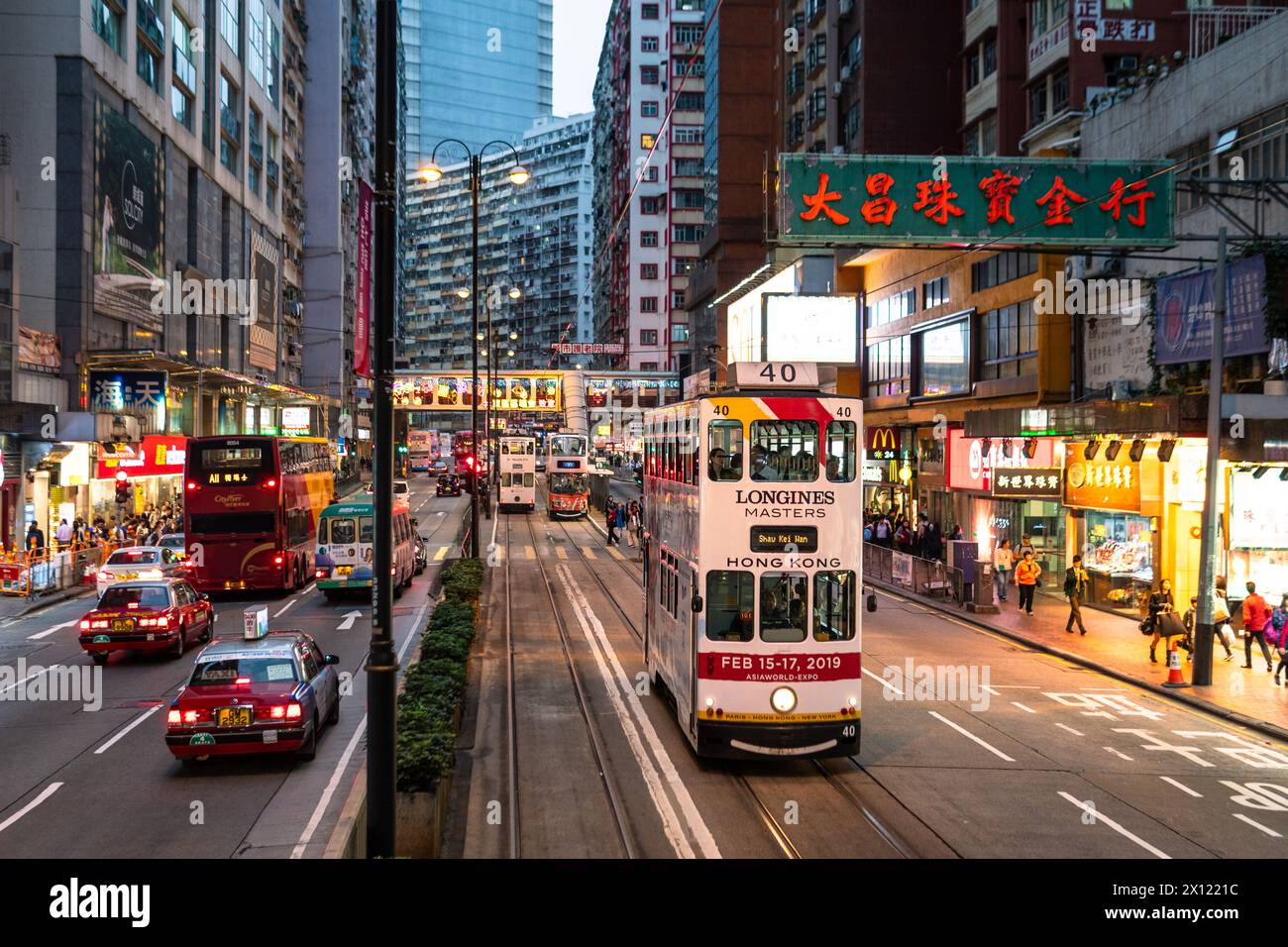 North Point, Hong Kong - March 15 2019: A double-deck tram drives through the crowded North Point district at dusk in Hong Kong island, China Stock Photo