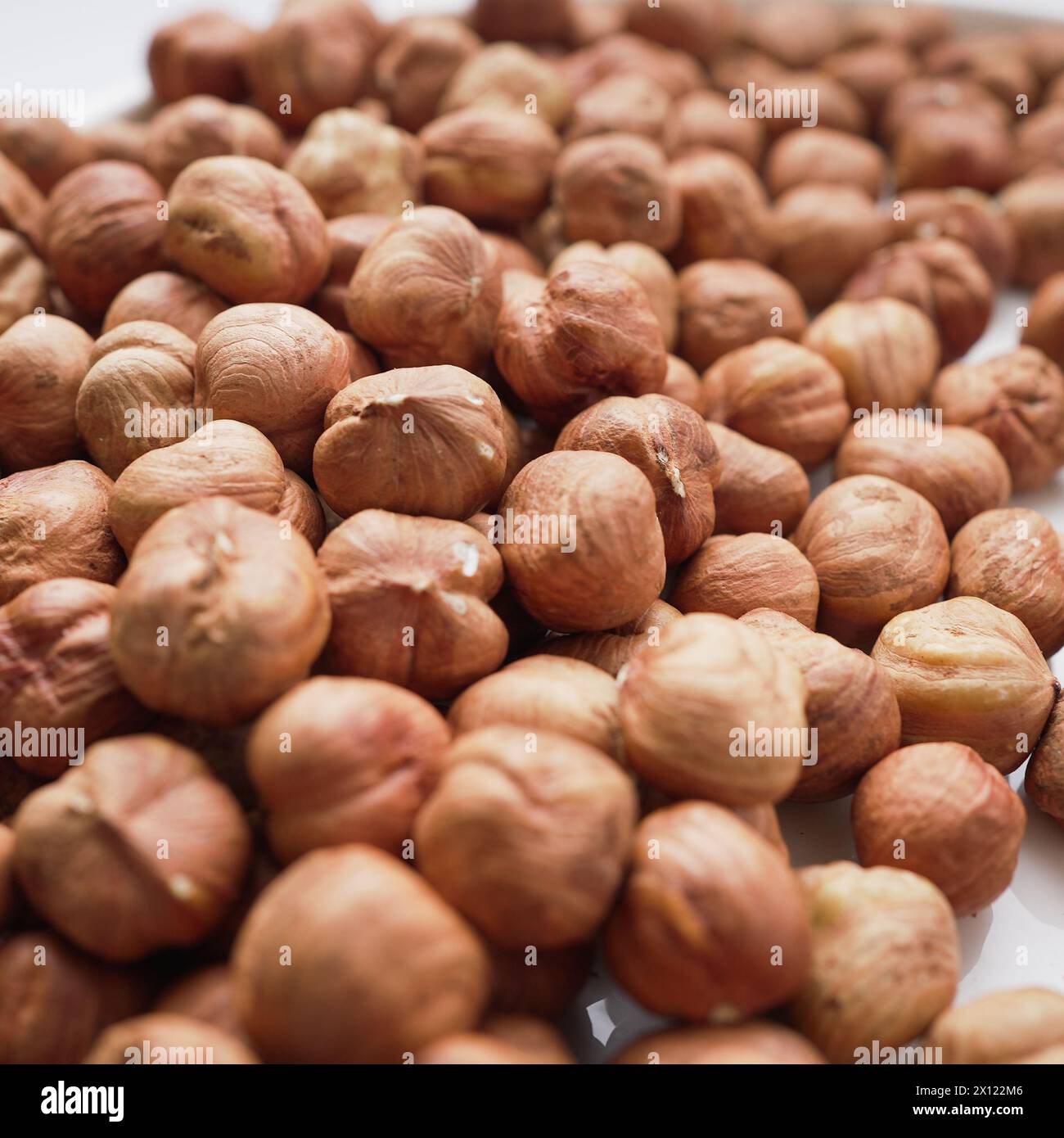 A close-up view of a pile of hazelnuts, showcasing their rich texture and warm, brown tones, perfect for culinary themes Stock Photo