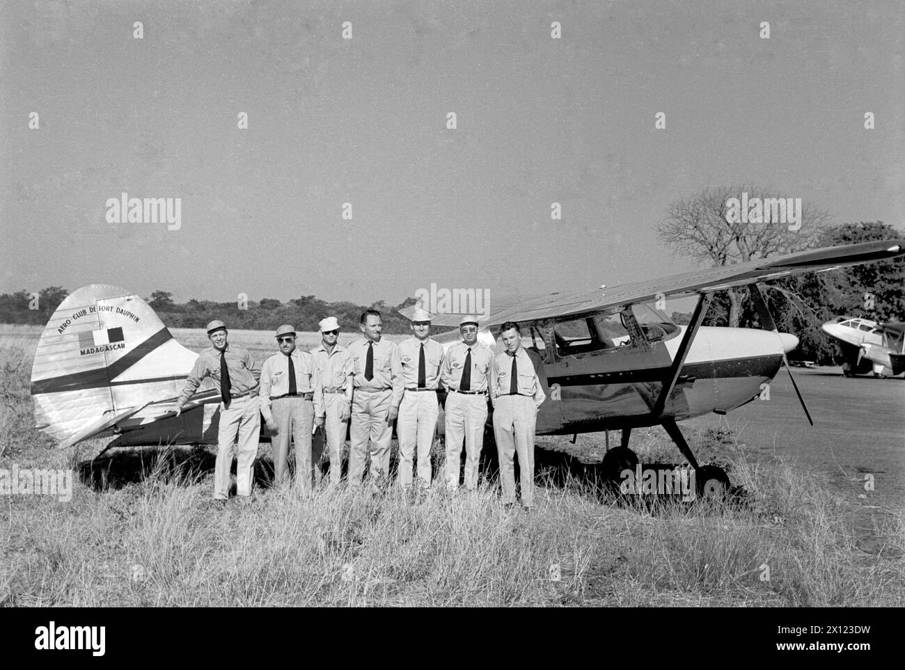 French Colonists or Colonial Members of the Aero Club de Fort Dauphin posing in Front of a Cessna 170 Light Airplane, Plane or Aircraft (produced from 1948-1956) at the Airfield or Airport of Fort Dauphin Madagascar. Vintage or Historic Monochrome or Black and White Image c1960. Stock Photo