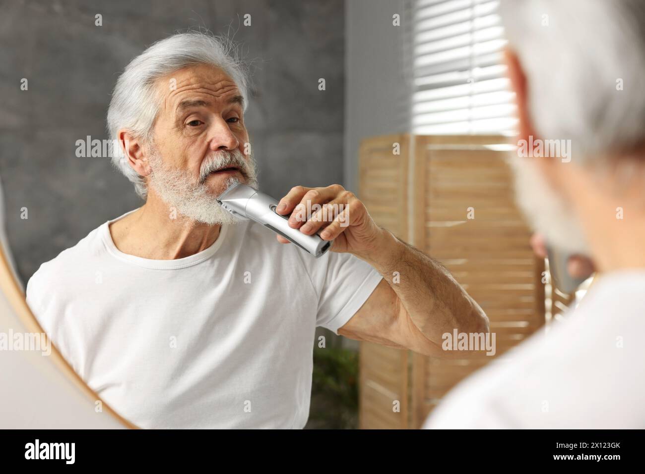 Senior man trimming beard near mirror in bathroom Stock Photo Alamy