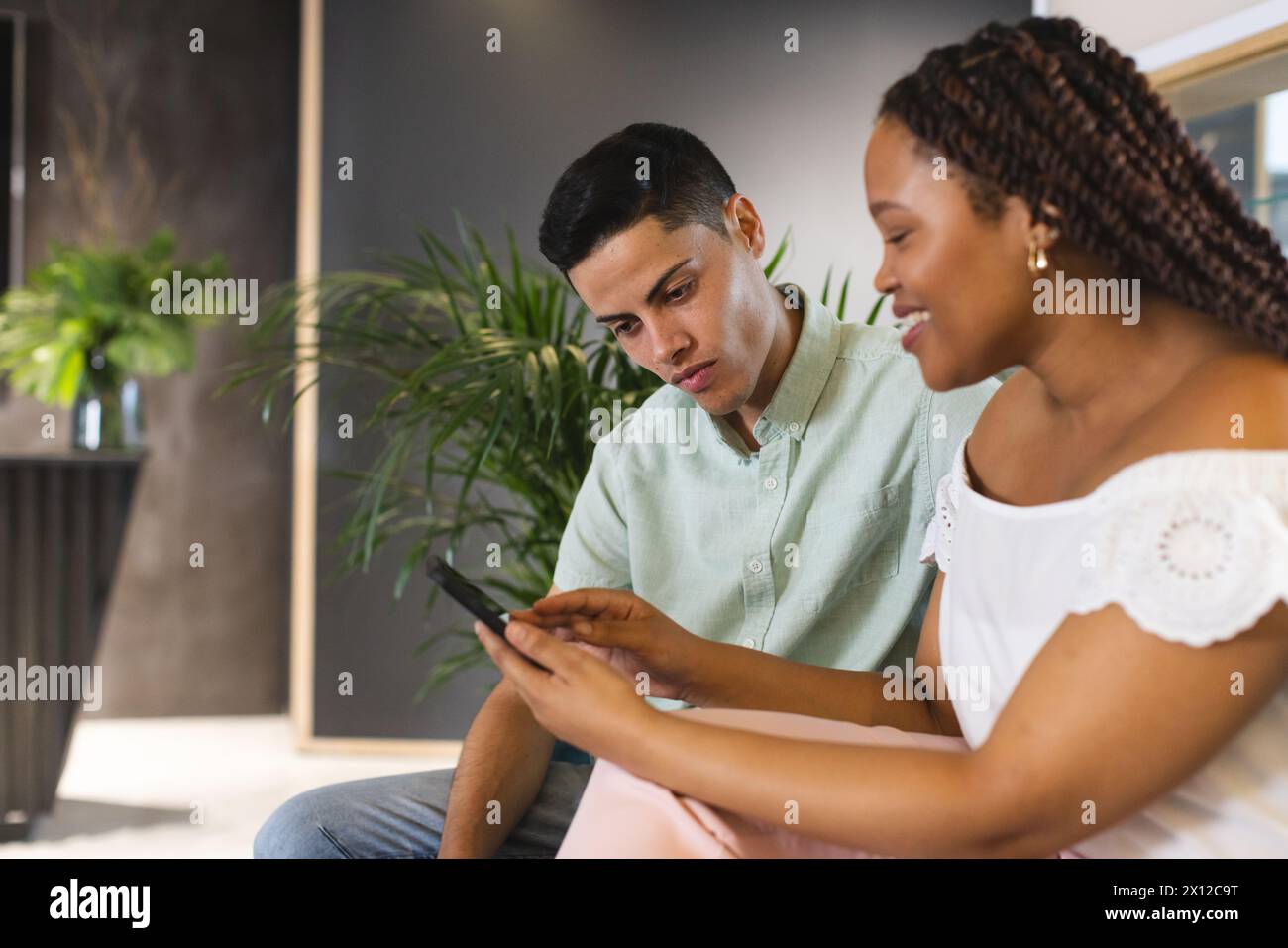 Biracial colleagues looking at smartphone together in a modern business office Stock Photo