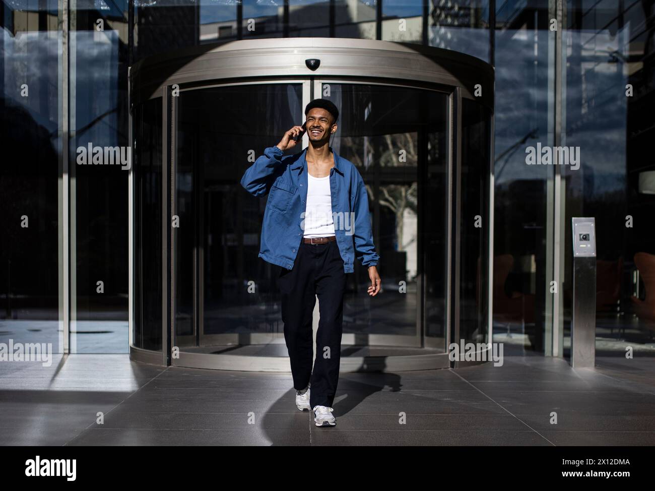 Smiling young man calling with phone leaving entrance modern bus Stock Photo