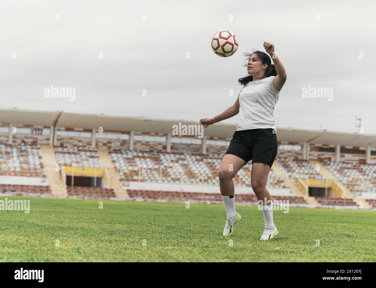Young woman kicking soccer ball while playing soccer Stock Photo - Alamy