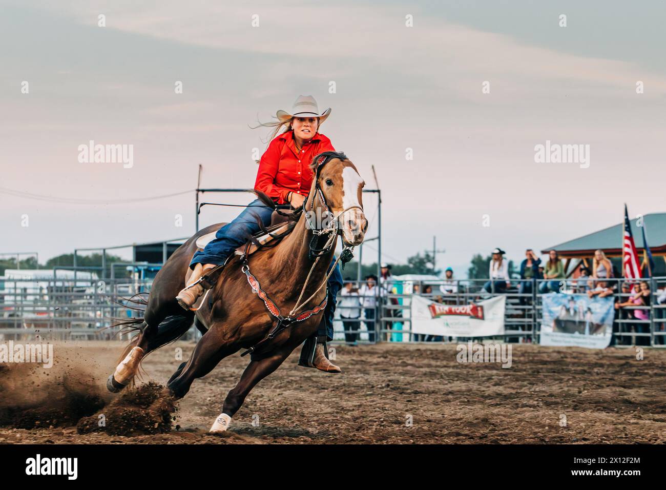 Cowgirl riding horse during barrel racing at county fair rodeo Stock Photo