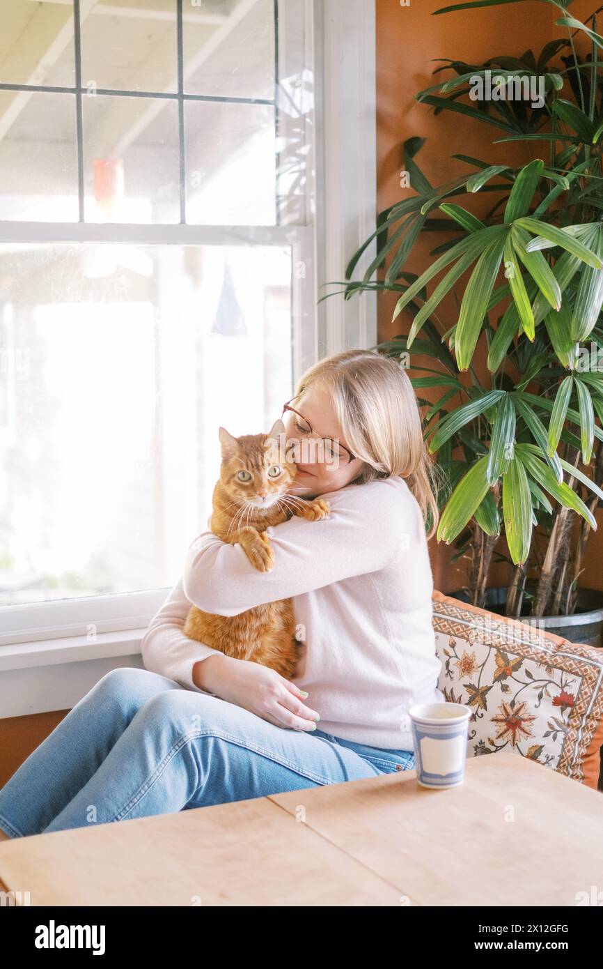 Woman lovingly embracing her ginger cat Stock Photo