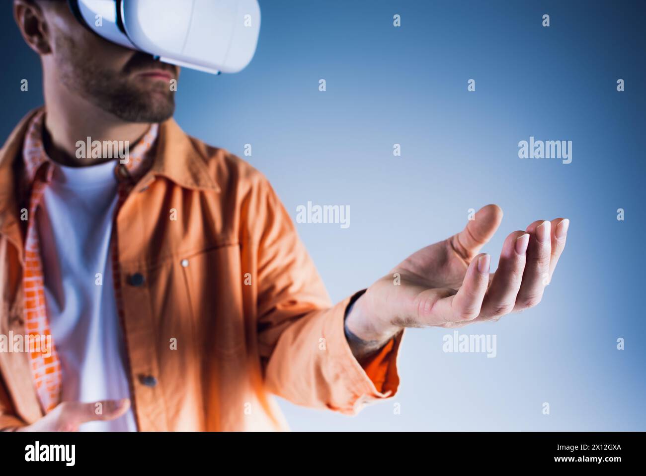 A man in a studio setting wearing a virtual reality glasses, exploring the Metaverse. Stock Photo