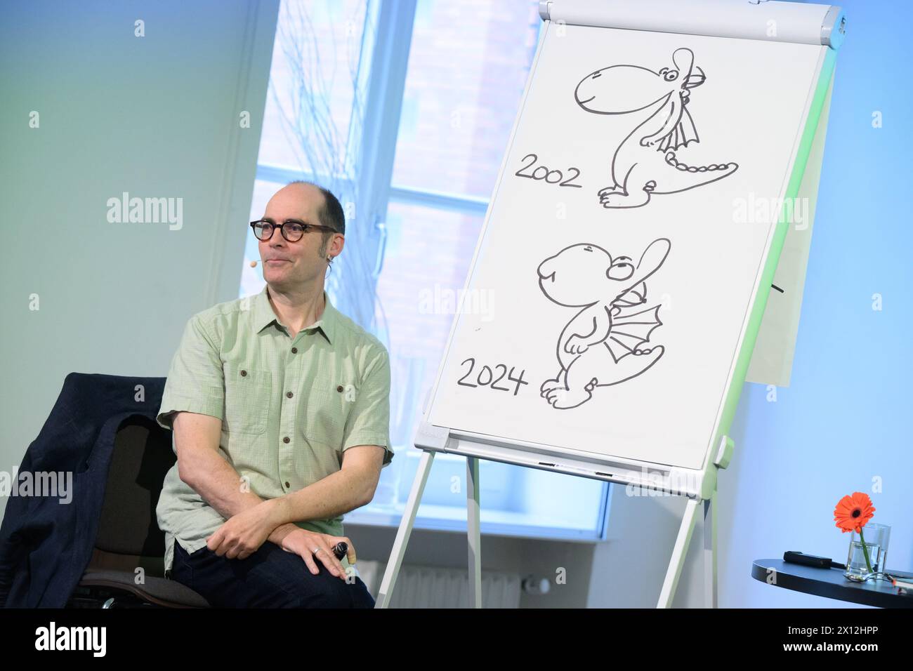 Hanover, Germany. 15th Apr, 2024. Children's book author Ingo Siegner shows how his book character Dragon Coconut has changed between 2002 and 2024 at a reading for primary school children at the Künstlerhaus Hannover. To mark the 70th anniversary of the Friedrich-Bödecker-Kreis Niedersachsen (FBK), 70 readings by authors for nurseries and schools in Lower Saxony are taking place. Children's book author Ingo Siegner read from his Drache-Kokosnuss books. Credit: Julian Stratenschulte/dpa/Alamy Live News Stock Photo