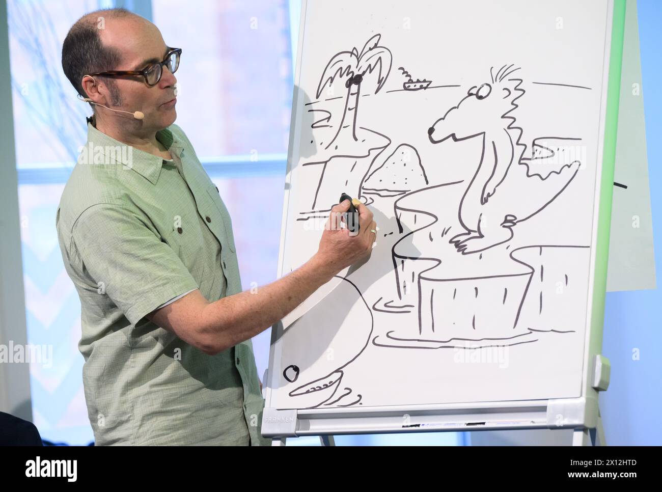 Hanover, Germany. 15th Apr, 2024. Children's book author Ingo Siegner shows how he invented his book character Dragon Coconut in 2000 at a reading for primary school children at the Künstlerhaus Hannover. To mark the 70th anniversary of the Friedrich-Bödecker-Kreis Niedersachsen (FBK), 70 readings by authors for nurseries and schools in Lower Saxony are taking place. Children's book author Ingo Siegner read from his Dragon Coconut books. Credit: Julian Stratenschulte/dpa/Alamy Live News Stock Photo