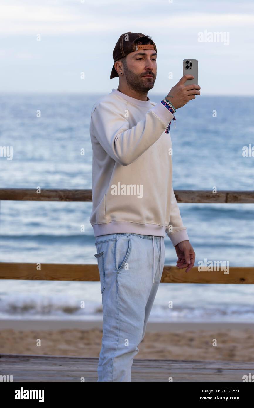 Man wearing casual with his cap backwards taking selfie on the beach Stock Photo