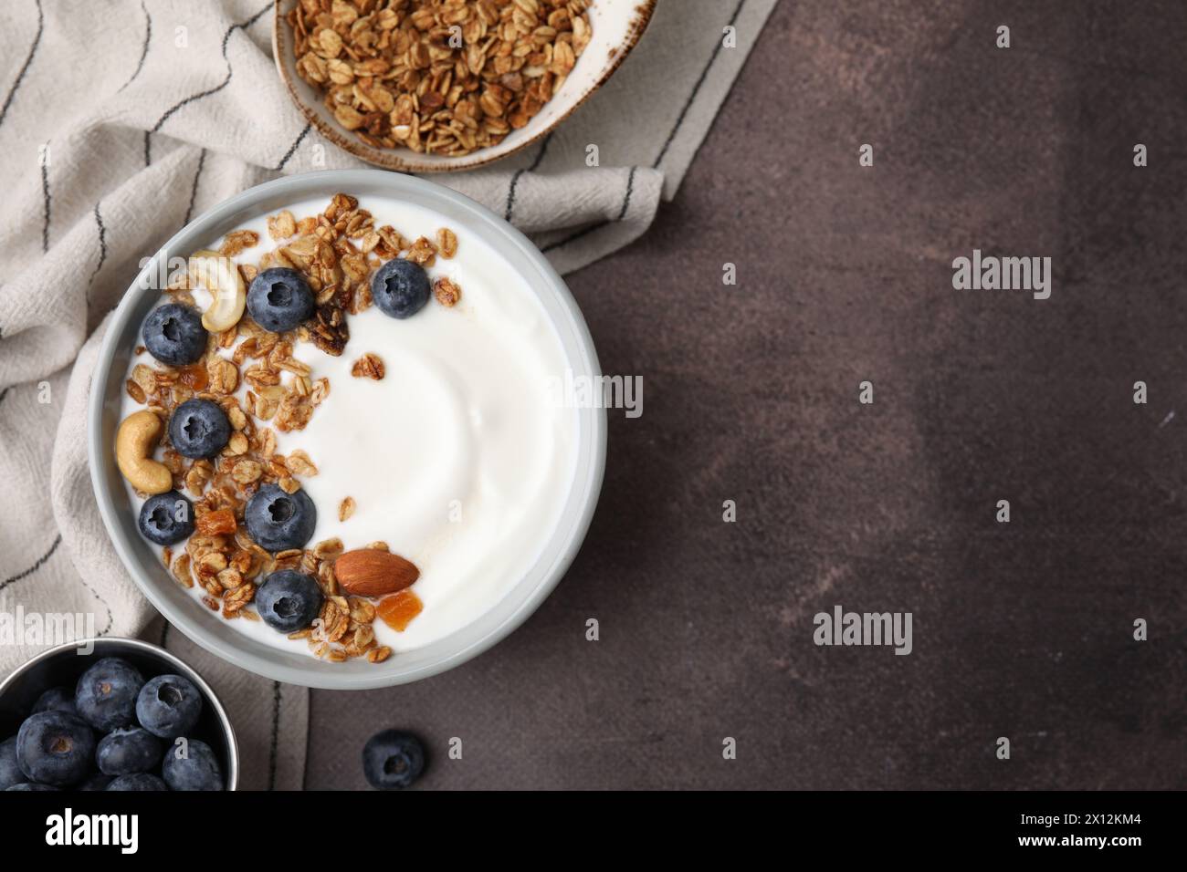 Bowl with yogurt, blueberries and granola on grey table, top view. Space for text Stock Photo