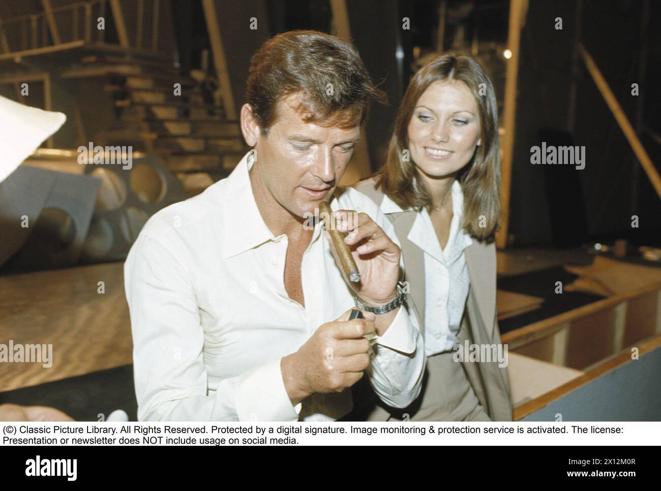 Sir Roger Moore , 1927-2017 during a media event in connection with the recording of the feature film The man with the golden gun at Pinewood studios. Roger Moore is known for his role as agent James Bond, playing the character in seven feature films.  Actress Maud Adams plays the role of Andrea Anders in the movie. 1974. Stock Photo