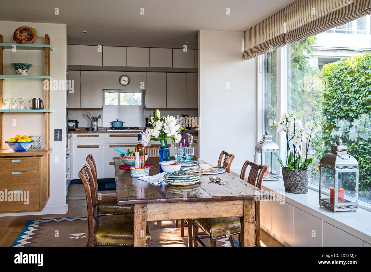 Wooden dining table and chairs in window of open plan kitchen in Chiswick Mall, Thames waterside residence, London, UK Stock Photo