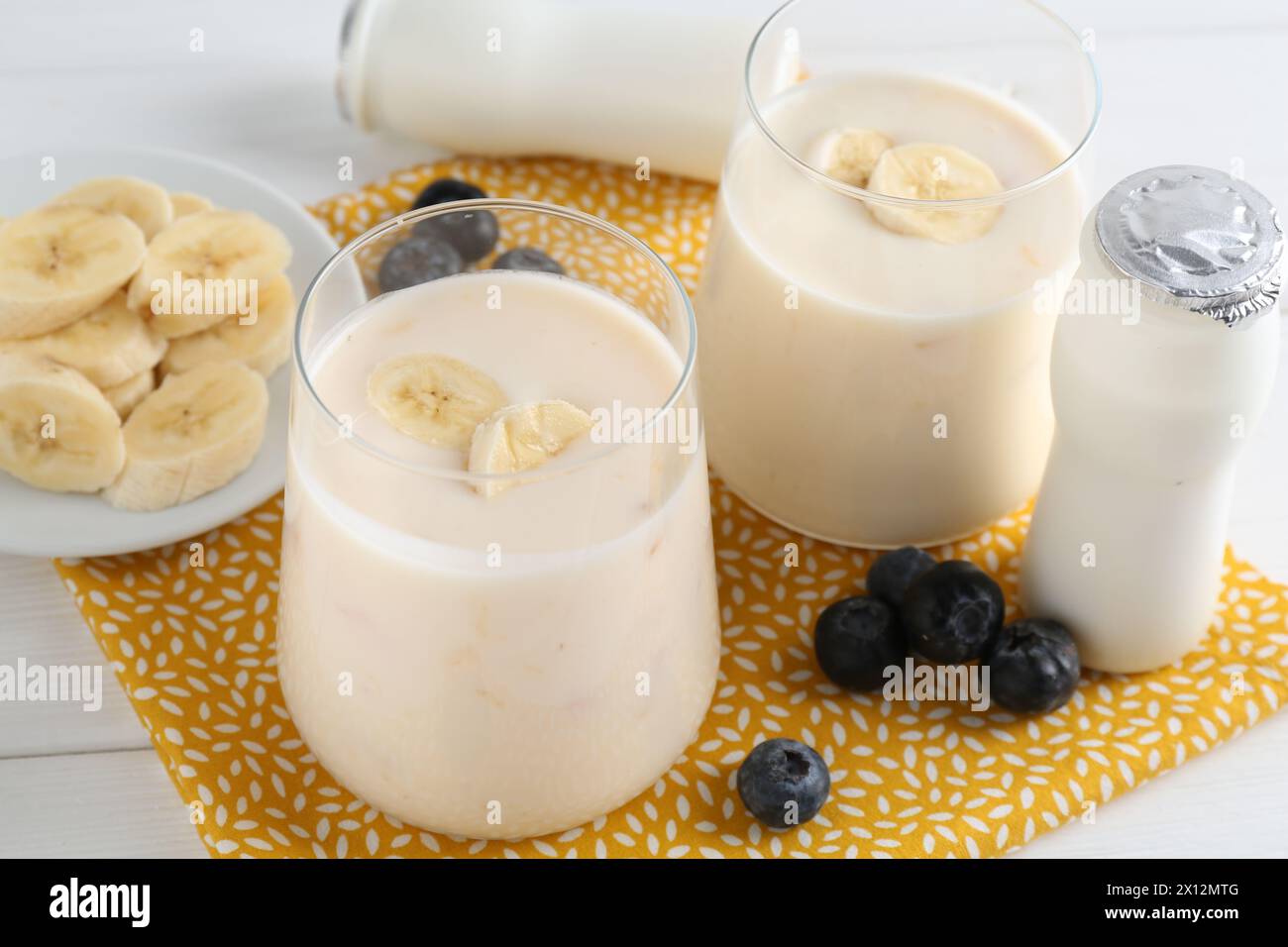Tasty yogurt, banana and blueberries on white wooden table, closeup Stock Photo