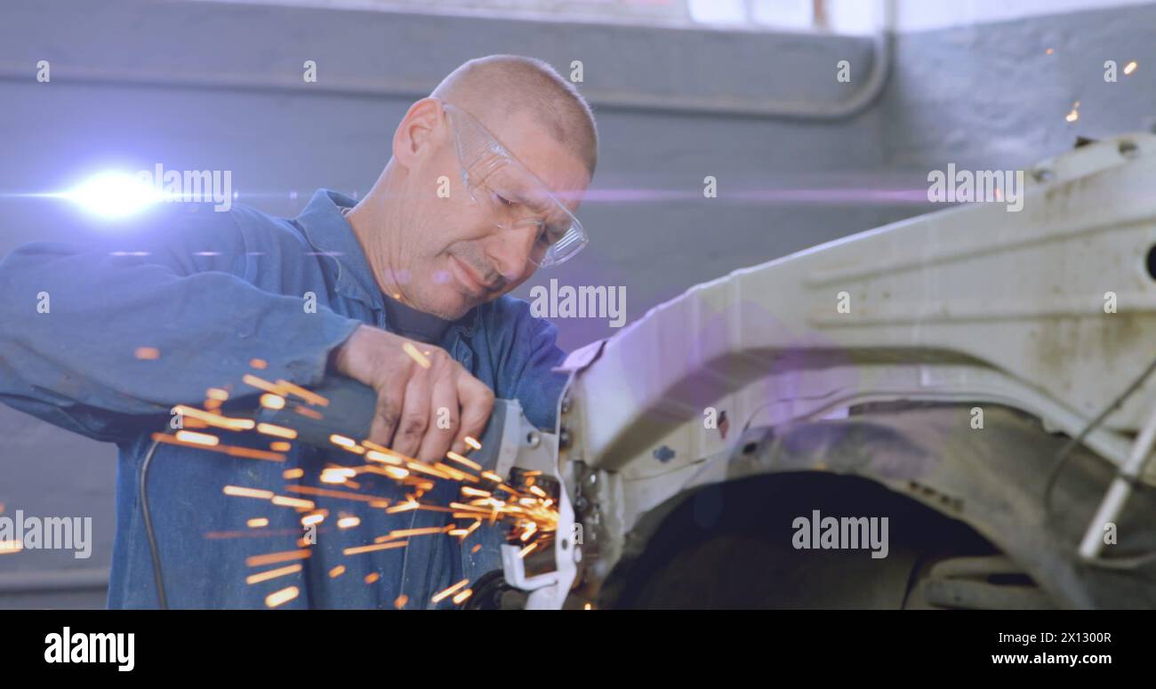 Image of blue light moving over male caucasian mechanic using grinding tool on car in garage Stock Photo
