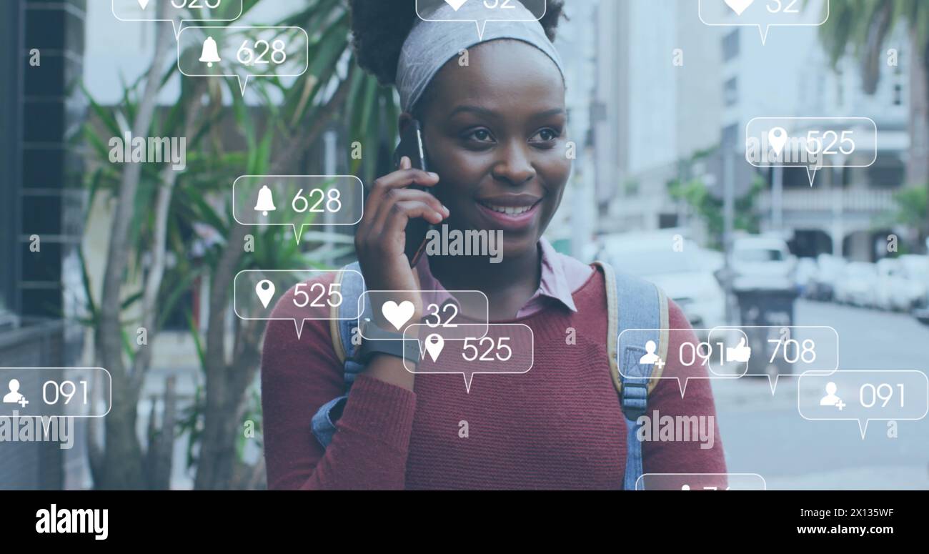 Image of social media icons with growing numbers over african american woman using smartphone Stock Photo