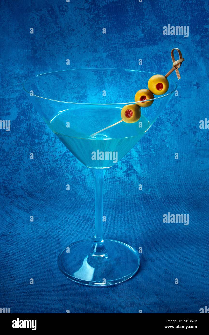 Martini. A glass of dirty martini cocktail with vermouth and olives, aperitif, on a blue background Stock Photo